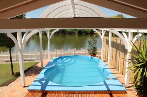 a blue swimming pool on a deck with a pergola at Holiday home in Bekesszentandras 20542 in Békésszentandrás