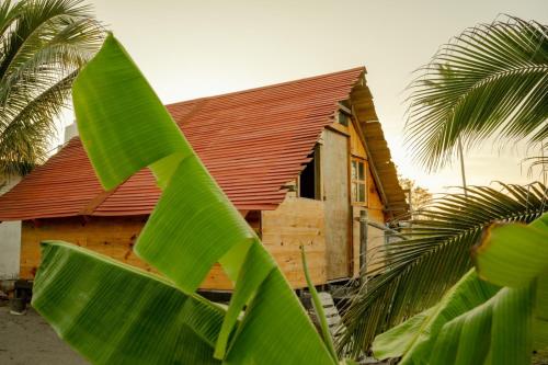 una casa con techo rojo y una palmera en Cabaña en la playa, en Monte Gordo