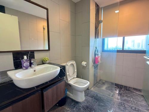 a bathroom with a sink and a toilet and a mirror at Landmark Seaview Cozy Family Suite with Balcony 6 Pax in Tanjong Tokong