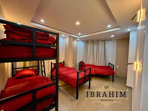een slaapkamer met 2 stapelbedden met rode lakens bij Dortoir Ibrahim in Tébessa
