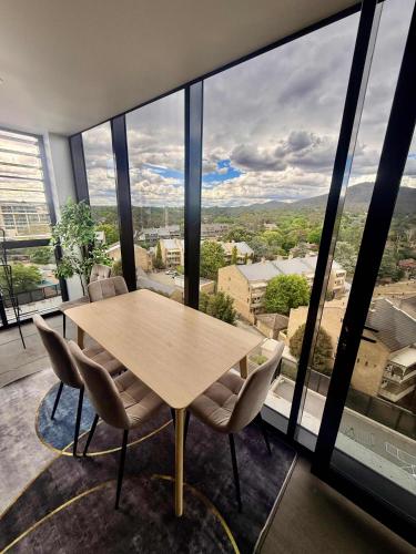 a table and chairs in a room with a large window at 2BR-2BR-2Cars -CBD-Pool-sleeps 6 in Canberra
