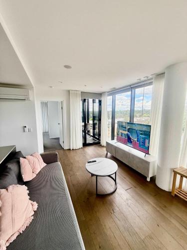 a living room with a couch and a flat screen tv at 2BR-2BR-2Cars -CBD-Pool-sleeps 6 in Canberra