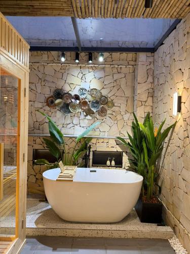 eine Badewanne im Bad mit einer Steinmauer in der Unterkunft Penthouse S202 Homestay BBQ Vinhomes Grand Park in Gò Công