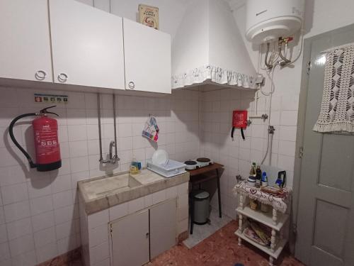 eine kleine Küche mit weißen Schränken und einer Spüle in der Unterkunft Casa da Tia Lena in Coimbra