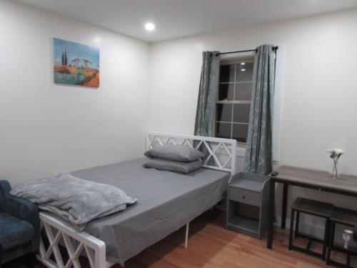 a bedroom with a bed and a table and a window at Cozy Rooms in Ozone Park in Brooklyn Manor