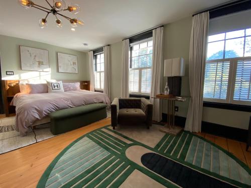 a bedroom with a bed and a chair and windows at Hattan House Boutique Hotel Bed & Breakfast in Niagara-on-the-Lake