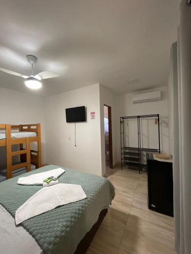 a bedroom with two beds and a flat screen tv at Pousada VKG Suites in São Pedro da Aldeia