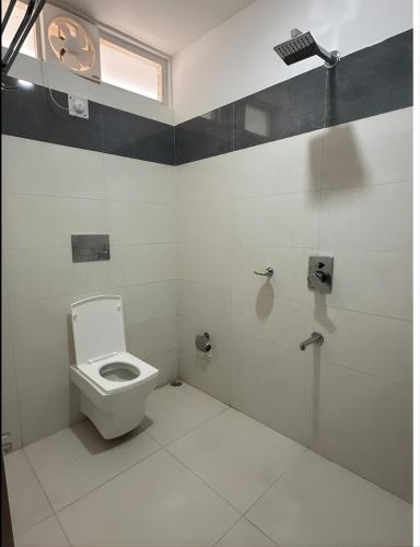a white bathroom with a toilet and a shower at Teplong The Paix, Kaziranga National Park in Sakmuthi