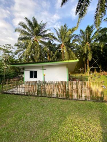 a white house with palm trees behind a fence at บ้านเพื่อนโฮมสเตย์ เขาพนม2 