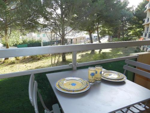 una mesa con platos y vasos en el balcón en Studio à Bormes-les-Mimosas avec balcon et parking privatif - FR-1-251-886, en La Favière