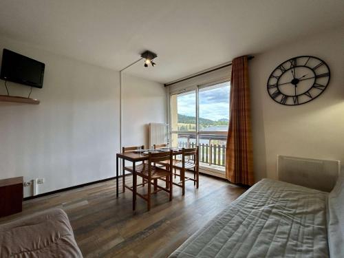 un soggiorno con un tavolo e un orologio a parete di Studio 4 pers. proche pistes, commerces, WiFi - FR-1-525-305 a Superdevoluy