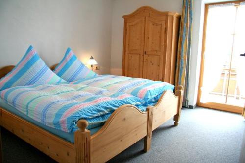 a bedroom with a bed with a wooden frame and a window at Landhaus Suntheim in Wertach