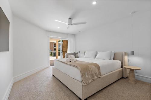 una camera da letto bianca con un letto grande e un tavolo di Serenity Apartments Noosa a Noosa Heads