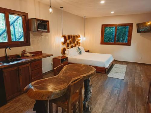 a bedroom with a bed and a kitchen with a sink at Hotel Cabañas Aldea Maya in Xpujil