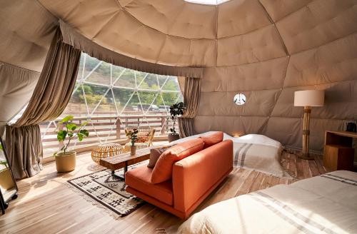 Zimmer mit einem Bett und einem Sofa in einem Zelt in der Unterkunft Glampseason in Sendai