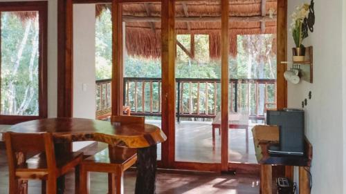 ein Esszimmer mit einem Holztisch und einem Fenster in der Unterkunft Hotel Cabañas Aldea Maya in Xpujil