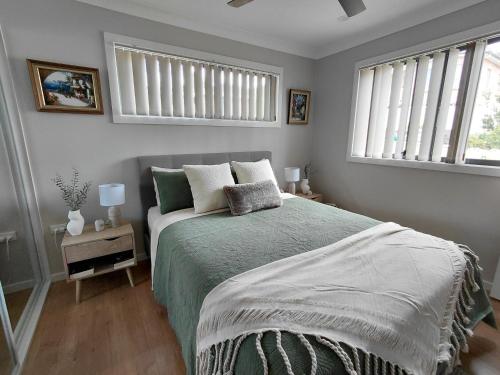 a bedroom with a bed and two windows at Ella Cottage - Relaxing romantic escape-Southern Highlands 