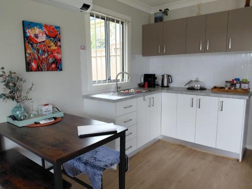 a kitchen with white cabinets and a wooden table at Ella Cottage - Relaxing romantic escape-Southern Highlands 