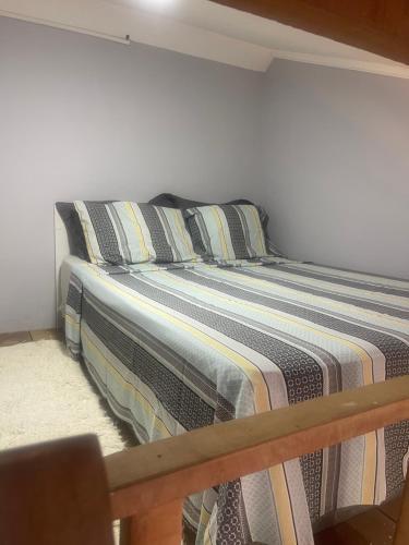 Bett mit gestreifter Bettwäsche und Kissen in einem Zimmer in der Unterkunft Lugar pra relaxar...Perto de tudo .. in Búzios