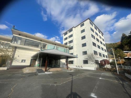 ein weißes Gebäude mit einem Parkplatz davor in der Unterkunft ホテル富士山水館富士山一望河口湖車で3分 in Fujikawaguchiko