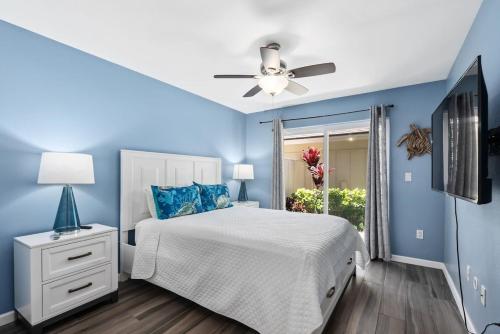een blauwe slaapkamer met een bed en een plafondventilator bij Home Away from Home Beach Villa in Honokai Hale