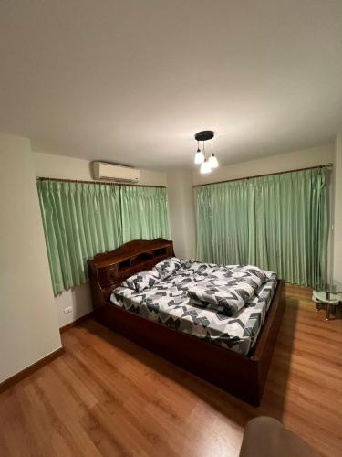 a bedroom with a bed and green curtains at Pailin Hill At Casa Ville Watcharapol in Bangkok