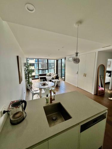 a kitchen with a sink and a living room at City-Self check in-Parking-Pool in Canberra