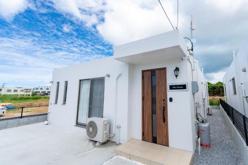 a white house with a door on a balcony at Villa Nuunu in Miyako-jima