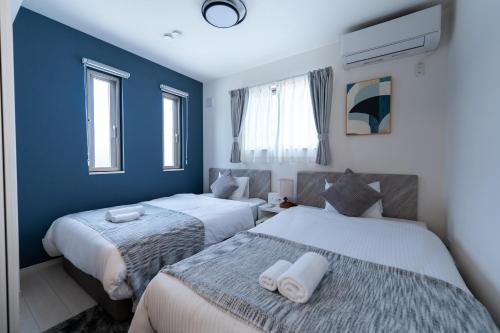 two beds in a room with blue walls and windows at Villa Nuunu in Miyako-jima