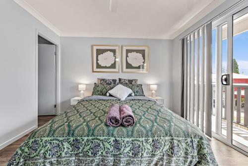 a bedroom with a bed with a green bedspread at Modern New Townhouse in Booval in Bundamba