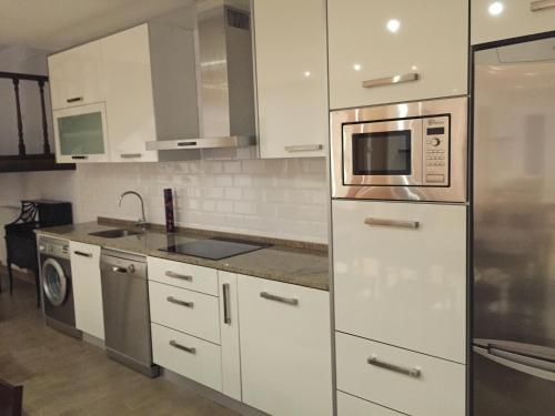 a kitchen with white cabinets and a microwave at Casa Rural El Zumaque in Pereña