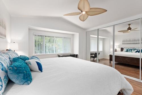 a white bedroom with a bed and a ceiling fan at Luxury Oasis Resort Villa in Honokai Hale