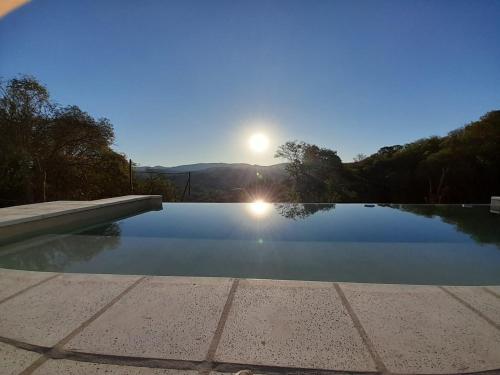 a swimming pool with the sun in the background at Wandritu in Río Ceballos