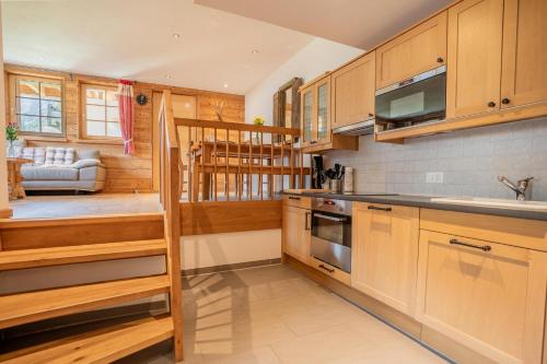 Marmo Apartment by HomeFlow في زيرمات: مطبخ مع خزائن خشبية ودرج يؤدي إلى غرفة المعيشة