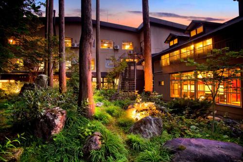 a house with a garden in front of a building at Ichirino Kogen Hotel Roan in Hakusan