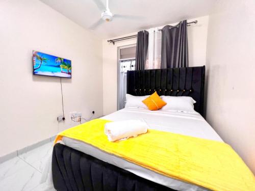 Un dormitorio con una cama grande con una manta amarilla. en Cosy apartments, en Mtwapa