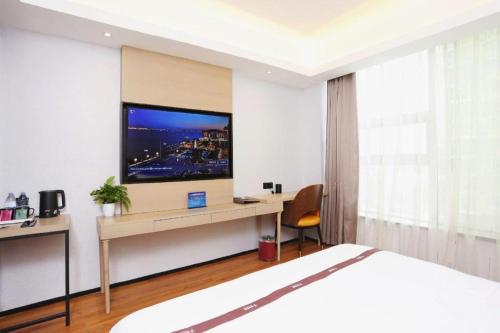 a bedroom with a bed and a desk with a tv at Gya Hotel Beijing Shunyi Yanjing Bridge in Shunyi
