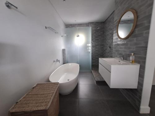 een badkamer met een wit bad en een wastafel bij Okeanós View - 4 Akrotiri in Ballito