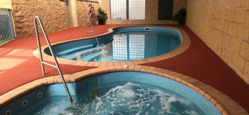 a large swimming pool in a building with a pool at Motel On A'Beckett in Inverloch