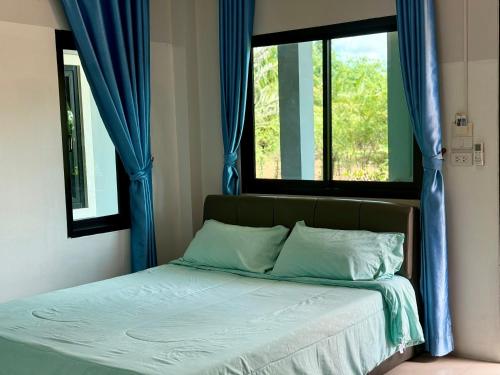 sypialnia z łóżkiem z niebieskimi zasłonami i oknem w obiekcie โรงแรมธารทิพย์ อินน์ หนองคาย รีสอร์ท w mieście Nong Khai