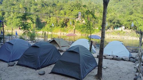 Eine Ansammlung von Zelten im Sand neben einem Fluss in der Unterkunft Tribe Riverbank Campsite in Dawki