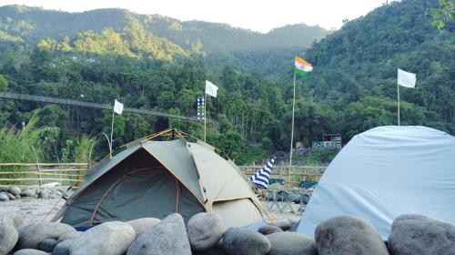 Ein Zelt, das auf einem Steinhaufen steht und mit Flaggen geschmückt ist. in der Unterkunft Tribe Riverbank Campsite in Dawki