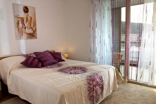 een slaapkamer met een bed met paarse kussens en een raam bij Apartment Belavista in Split