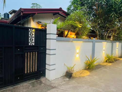 una casa con una puerta negra y una valla blanca en Weligama Surf Villa, en Weligama