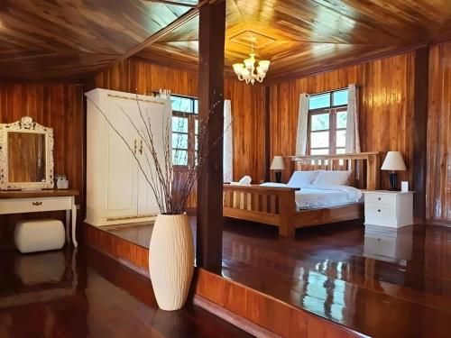 Ban Nong KhwangKirirath Resort的一间卧室设有一张床和一个大型花瓶