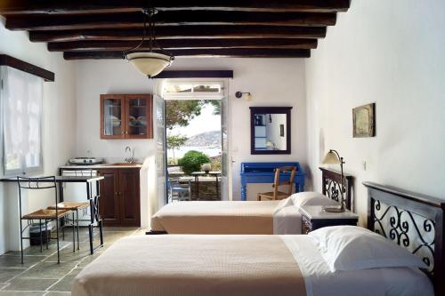 1 dormitorio con 2 camas y cocina con mesa en Fassolou, en Faros