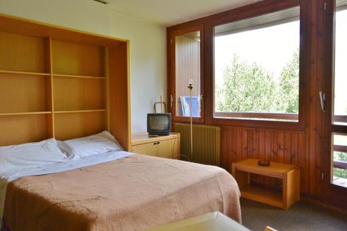 1 dormitorio con 1 cama, TV y ventana en Appartamenti La Maison de Vacances, en Breuil-Cervinia
