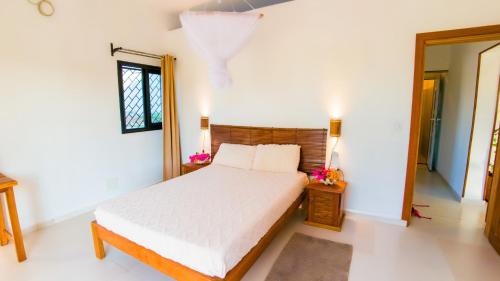 luxury villa in Nosy Be Ambaro في Ambaro: غرفة نوم بسرير أبيض ونافذة