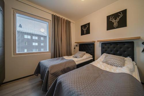 a hotel room with two beds and a window at Lomavuokra Alpine Chalets Tunturinlaita B9 in Levi