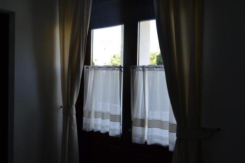 two windows with white curtains in a room at Casa de Oaspeți Sfântul Nicolae in Iaşi